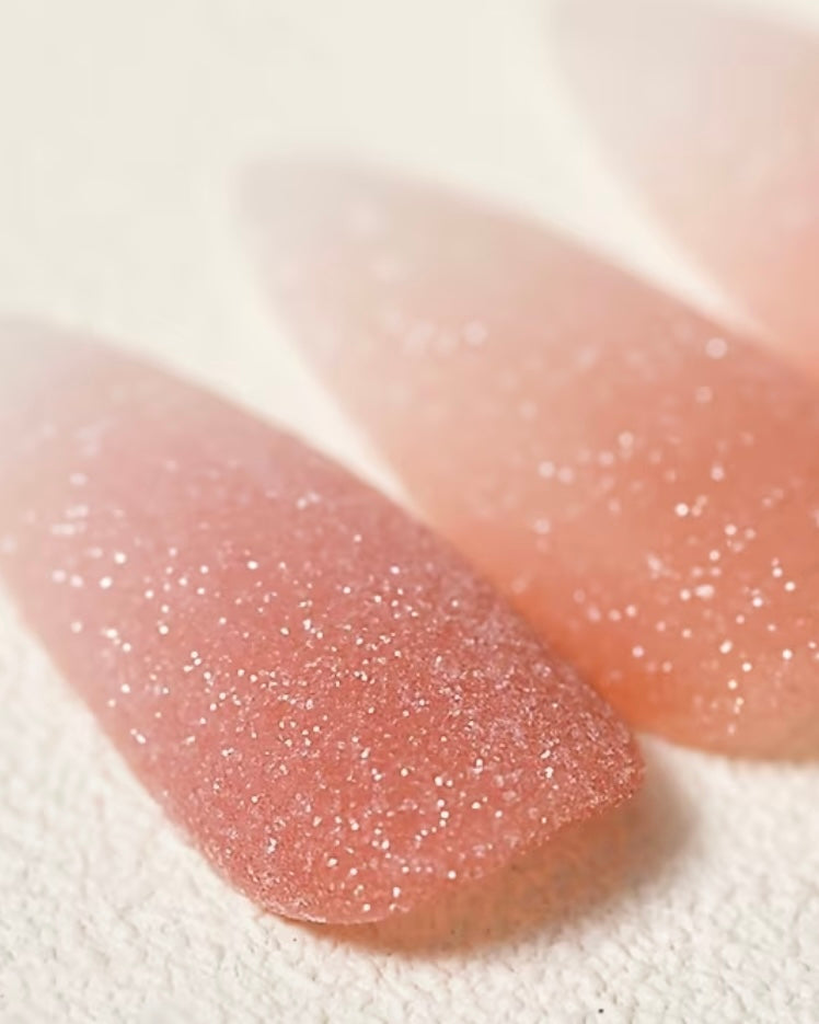 Gros plan sur un ongle en gel avec une manucure effet sucre blanche pailletée